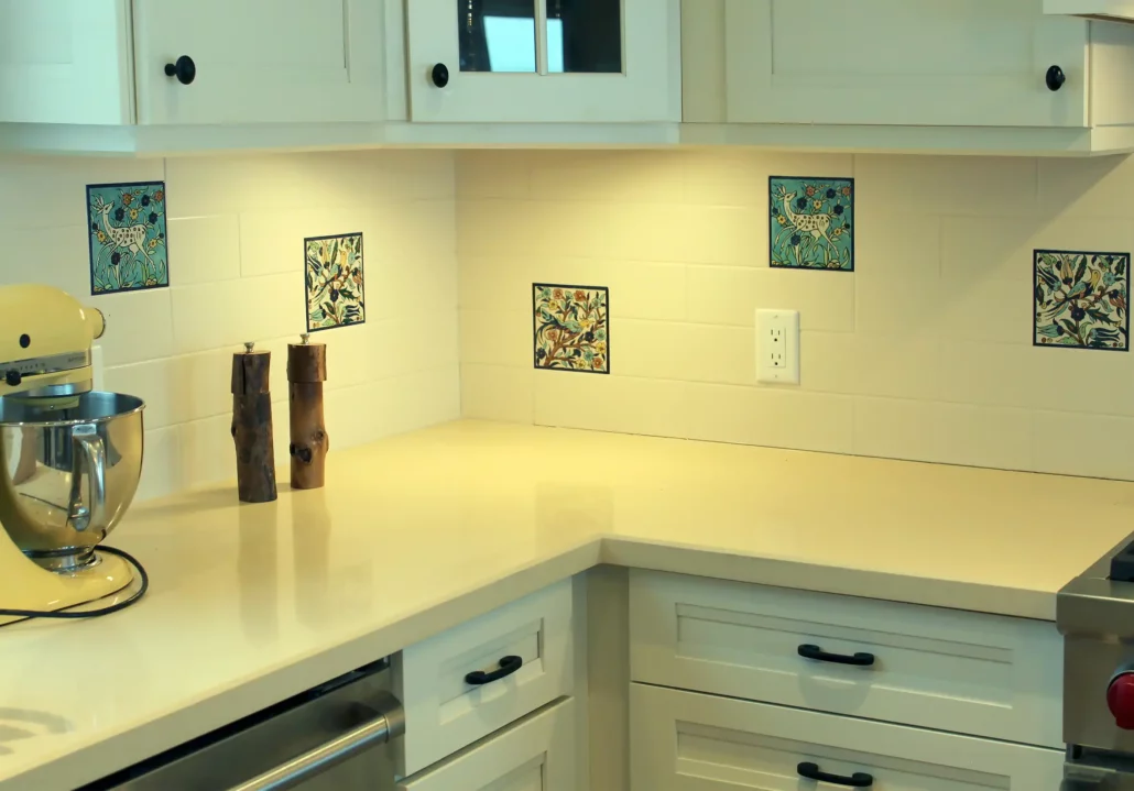 A kitchen backsplash with hand painted  accent tiles