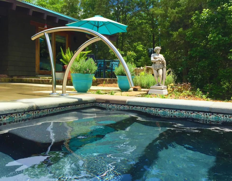 Patterned Balian waterline tiles beside submerged pool entry steps and a curved metal handrail