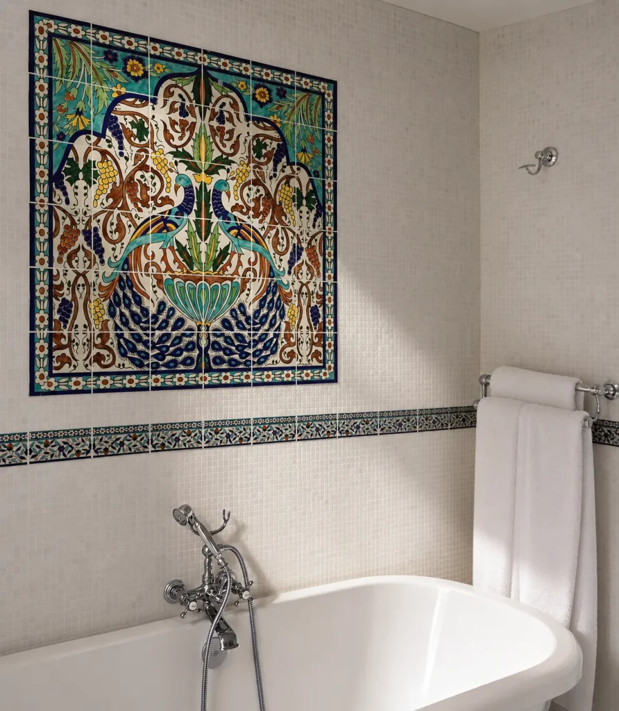 A hand painted tile mural in a small bathroom with 6x3 inch subway tiles running across the walls of teh shower area