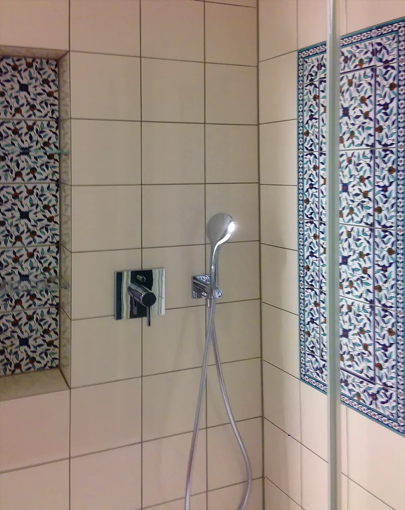 15x15 cm floral-patterned ceramic hand-decorated shower tiles in a small shower area