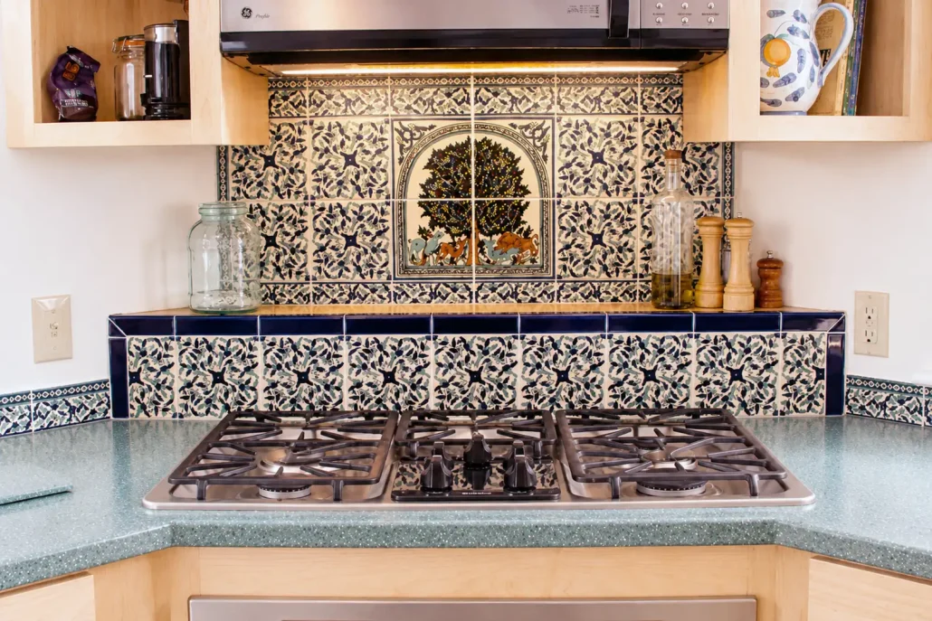 6x6 inch hand painted ceramic filed tiles surrounding a Tree of life tile mural on a kitchen backsplash in front of the cooktio