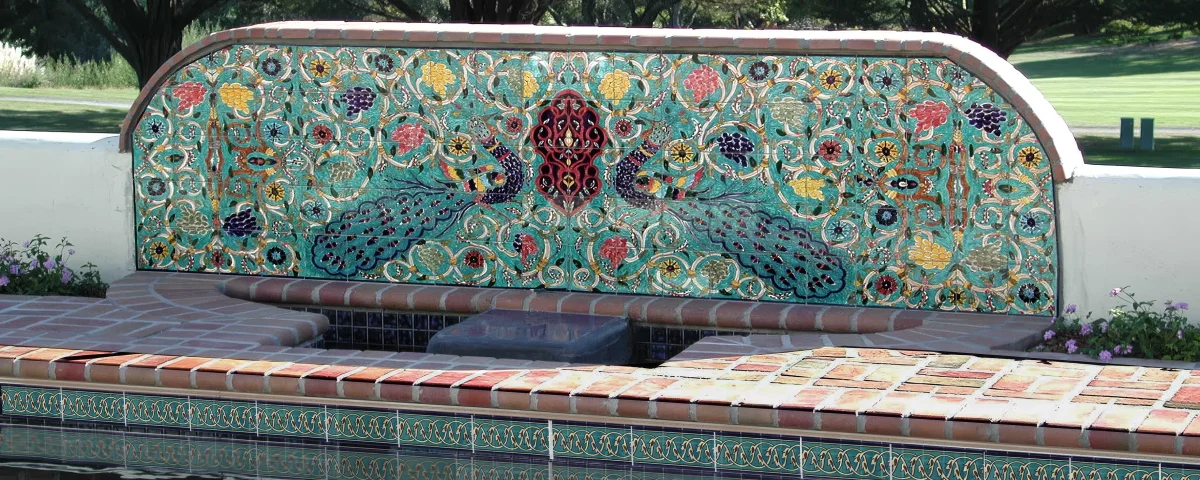 Decorative poolside fountain mural above a swimming pool waterline tile border