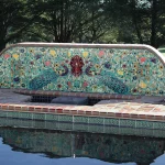 Decorative poolside fountain mural above a swimming pool waterline tile border