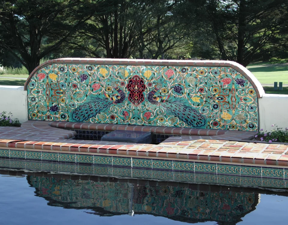 Decorative poolside fountain mural above a swimming pool waterline tile border