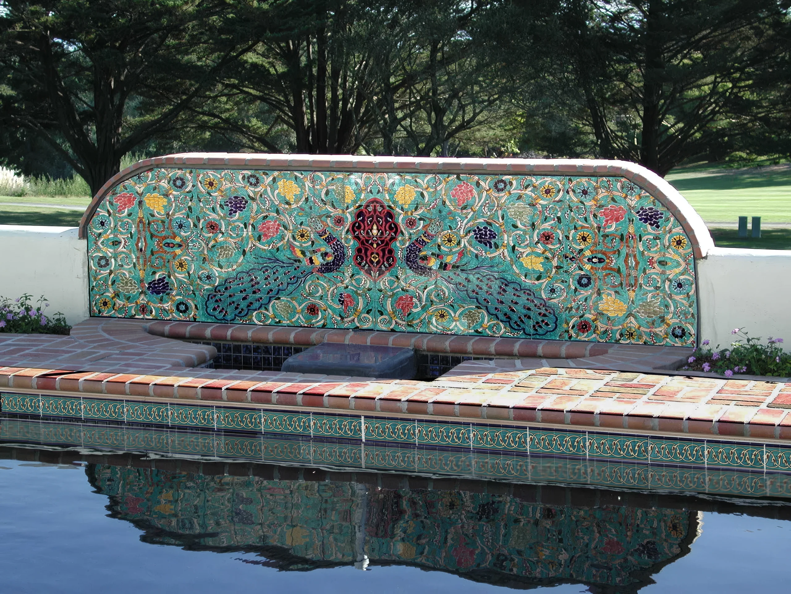 Decorative poolside fountain mural above a swimming pool waterline tile border