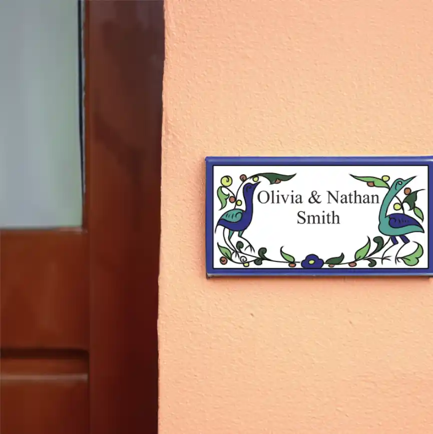 Hand-painted Armenian ceramic tile nameplate reading Olivia and Nathan Smith with peacock and floral border motifs in blue and green