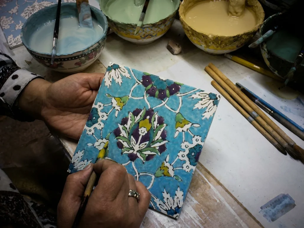 A talented artist hand-painting a 6x6 geometric and floralinch accent tile