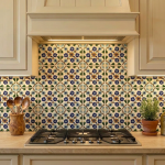 Hand-painted blue and ochre floral tile backsplash above a gas cooktop in a cream kitchen